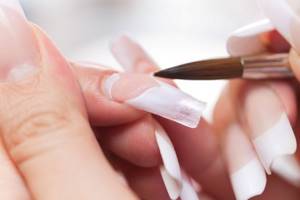 While the acrylic is still slightly plastic, use tweezers or your nails to gently press the nail on both sides